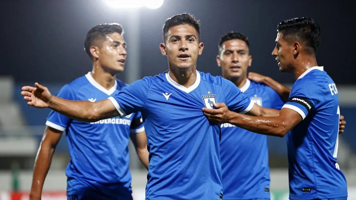 A 25-year-old Queretaro player, wearing a solid blue jersey, celebrates a goal with his teammates, photographed with an...