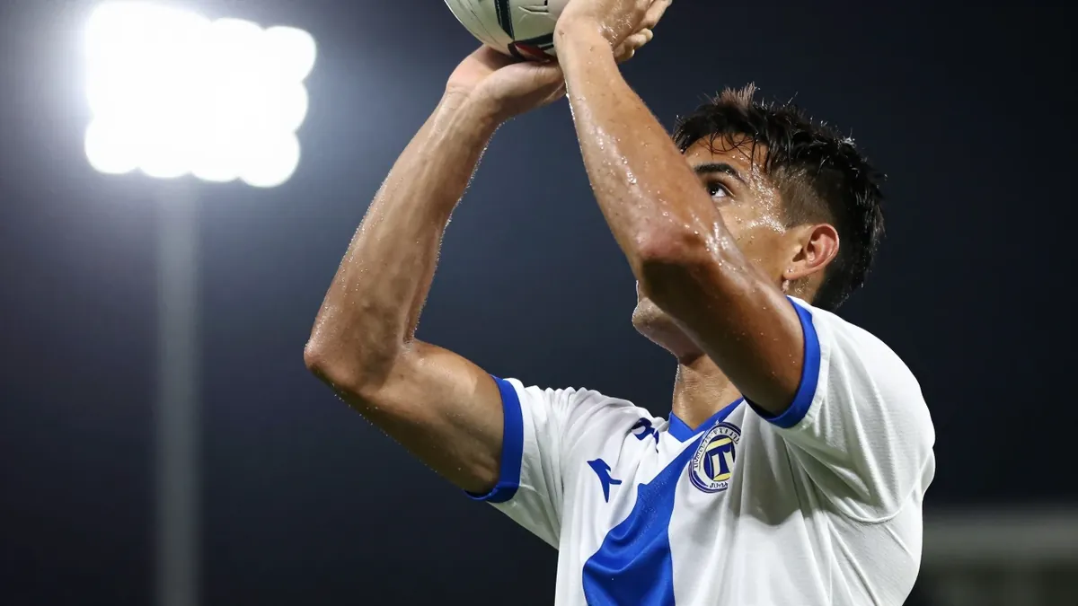 A close-up shot of an anonymous Queretaro player in a white jersey with a blue stripe, looking focused as he prepares to...