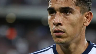 A close-up of a Queretaro player's face, looking concerned, with a blurred background of the stadium, taken with a 50mm...