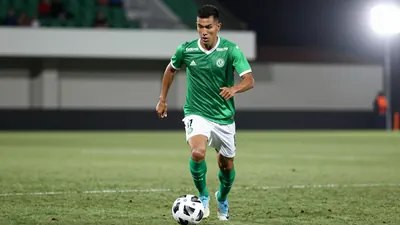 A photorealistic image of an anonymous Queretaro player in action, with a green jersey and white shorts, running towards...